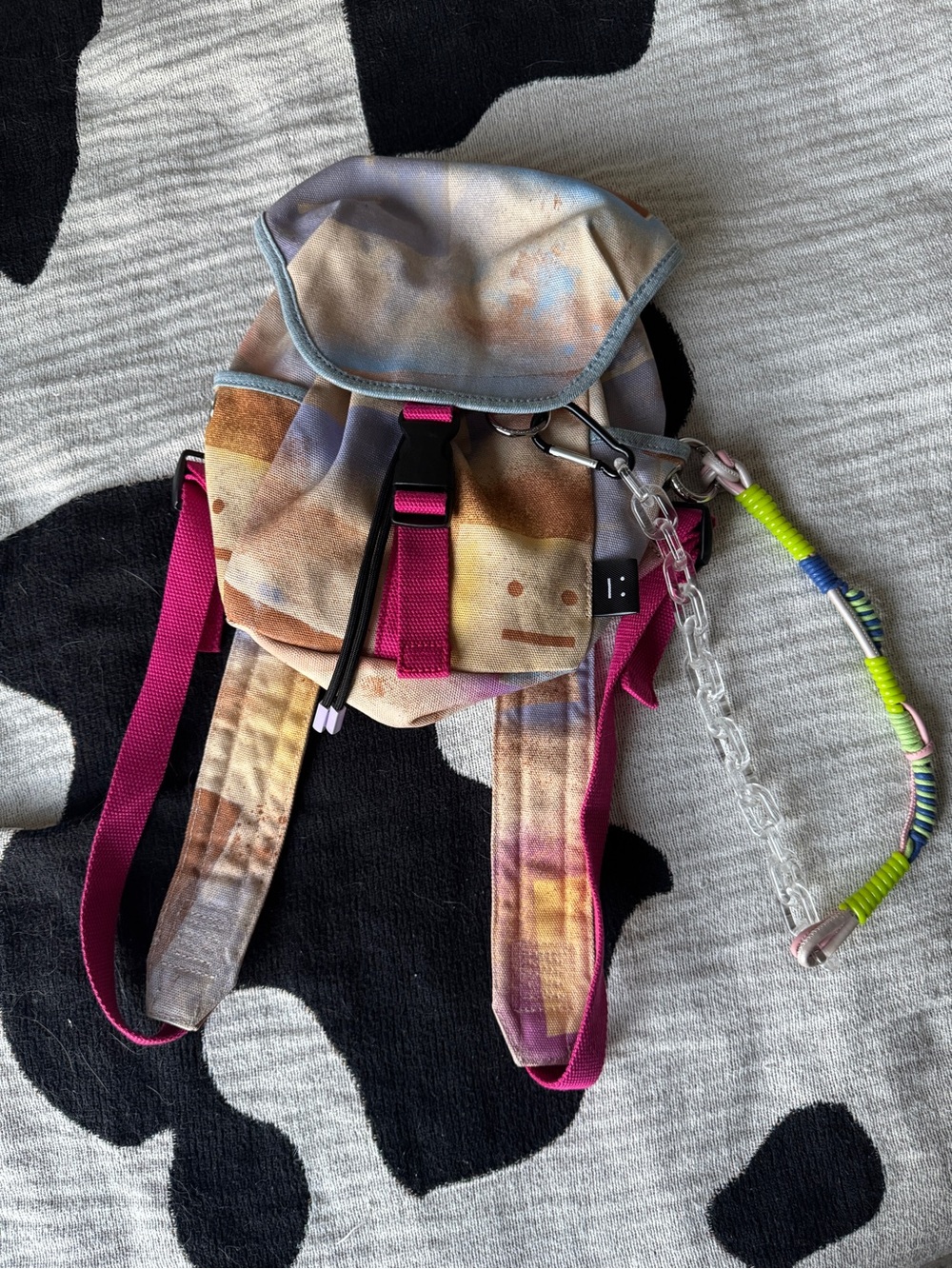 Acne multicolor tie-dye mini backpack with bright pink straps and clear chain